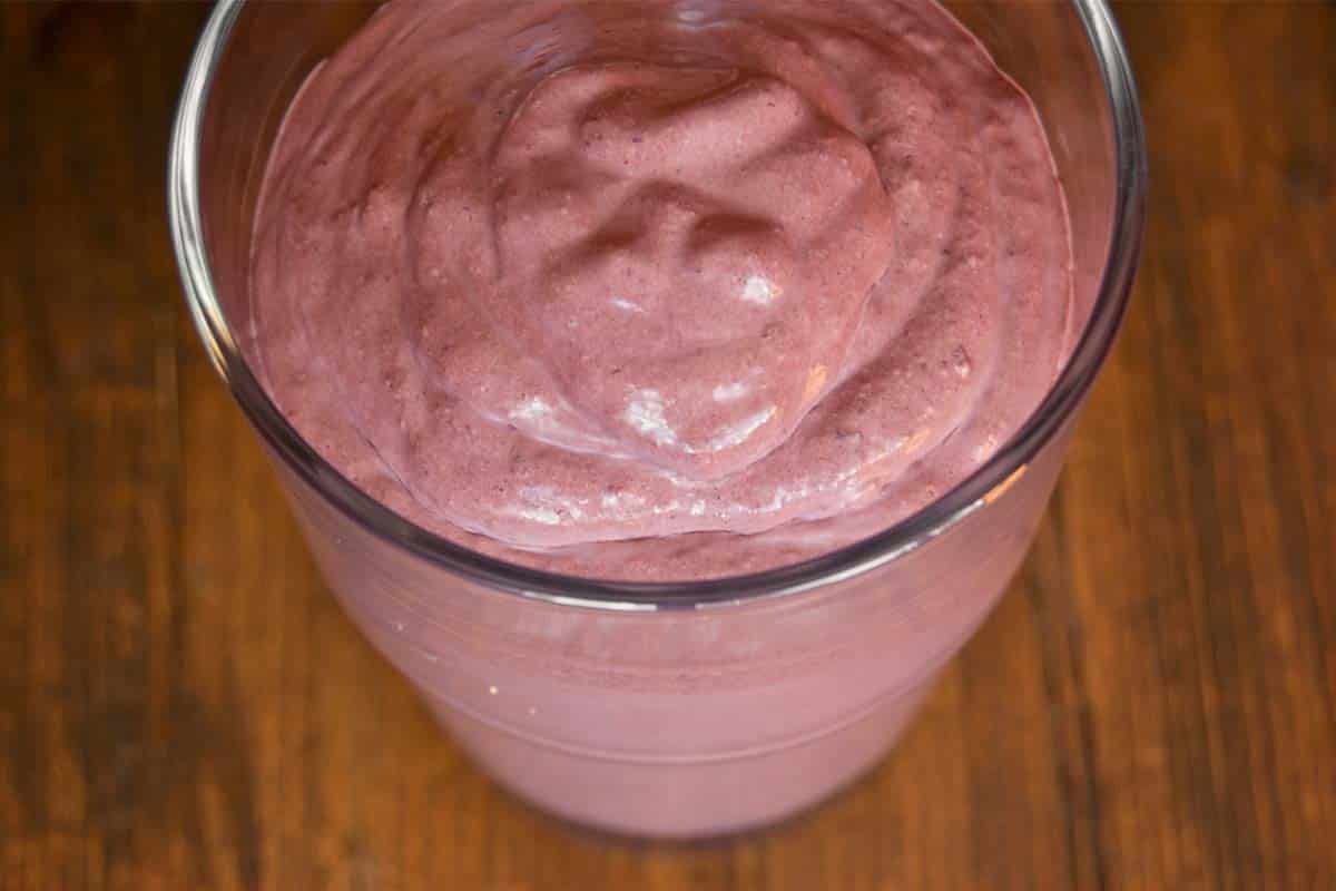 overhead view of Almond butter and chocolate blueberry smoothie in a glass on a wood table