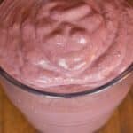 overhead view of a glass of Almond butter and chocolate blueberry smoothie on a wood table