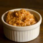 closeup of a ramekin filled with Almond butter dip on a wood table