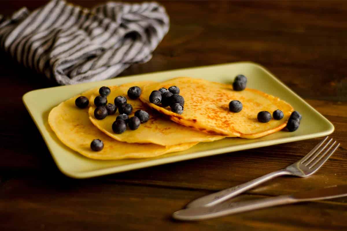 plate covered with Almond flour pancakes and blueberries on a wood table