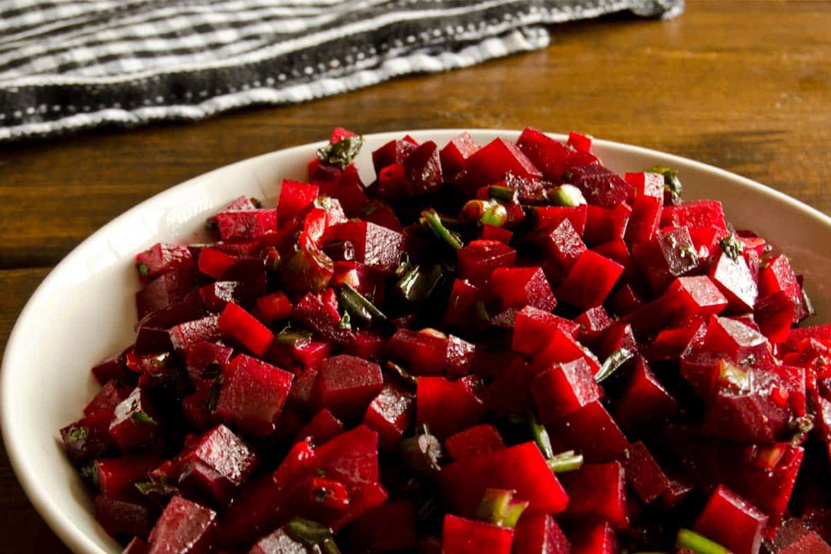 closeup of Beetroot salsa in a white bowl on a wood table