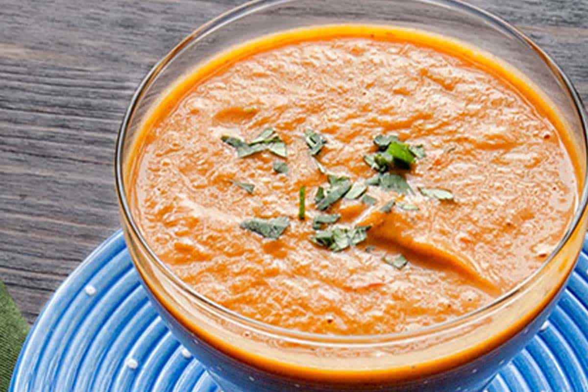 Butternut squash curry soup in a glass bowl on a wood table