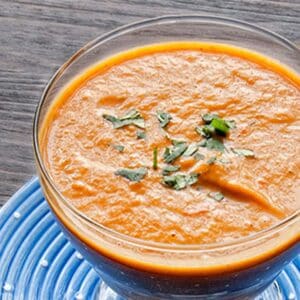 glass cup of Butternut squash curry soup on a wood table