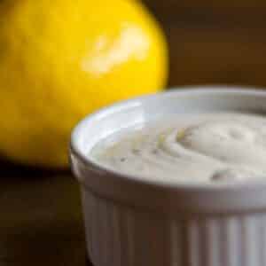 closeup of a white ramekin full of homemade Caesar dressing with a lemon in the background