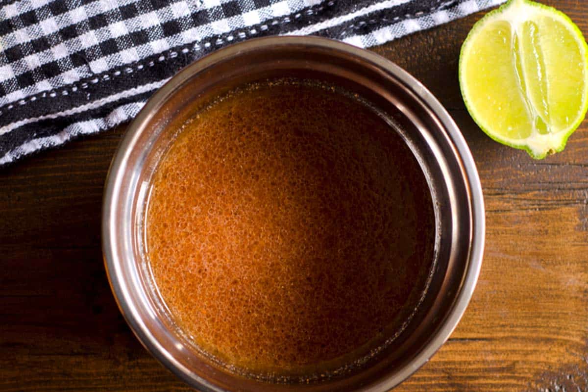 closeup of a small bowl of Cajun marinade on a table next to a slice of lime