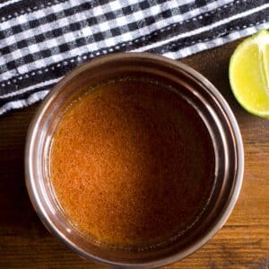 closeup of a bowl filled with Cajun marinade on a table nex tto a sliced lime