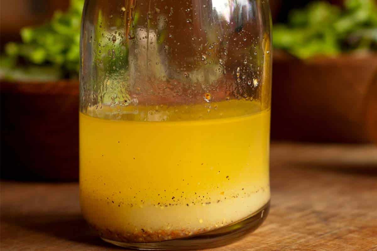 closeup of a glass carafe with Classic Lemon Vinaigrette on a wood table