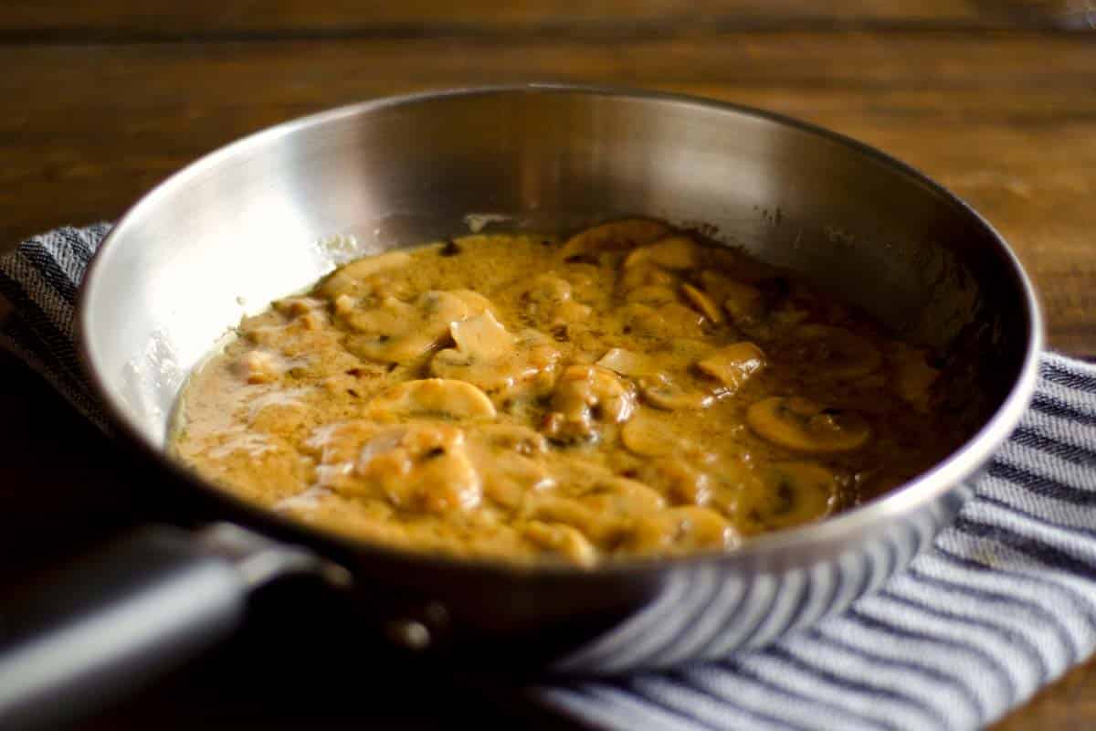 saucepan of Creamy Mushroom sauce on a wood table