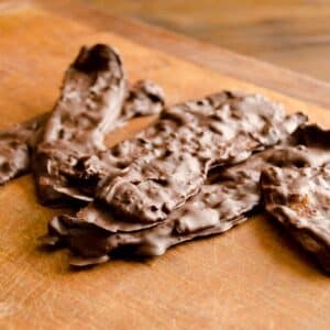 wood table with several pieces of Dark chocolate covered bacon stacked on it