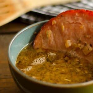 closeup of a blue bowl filled with French Onion Soup with Baked Ham