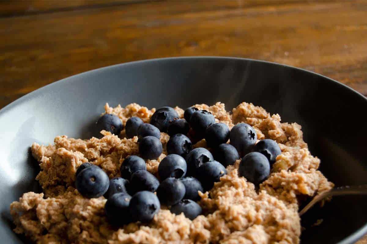 Grain-free oatmeal topped with blueberries in a grey bowl