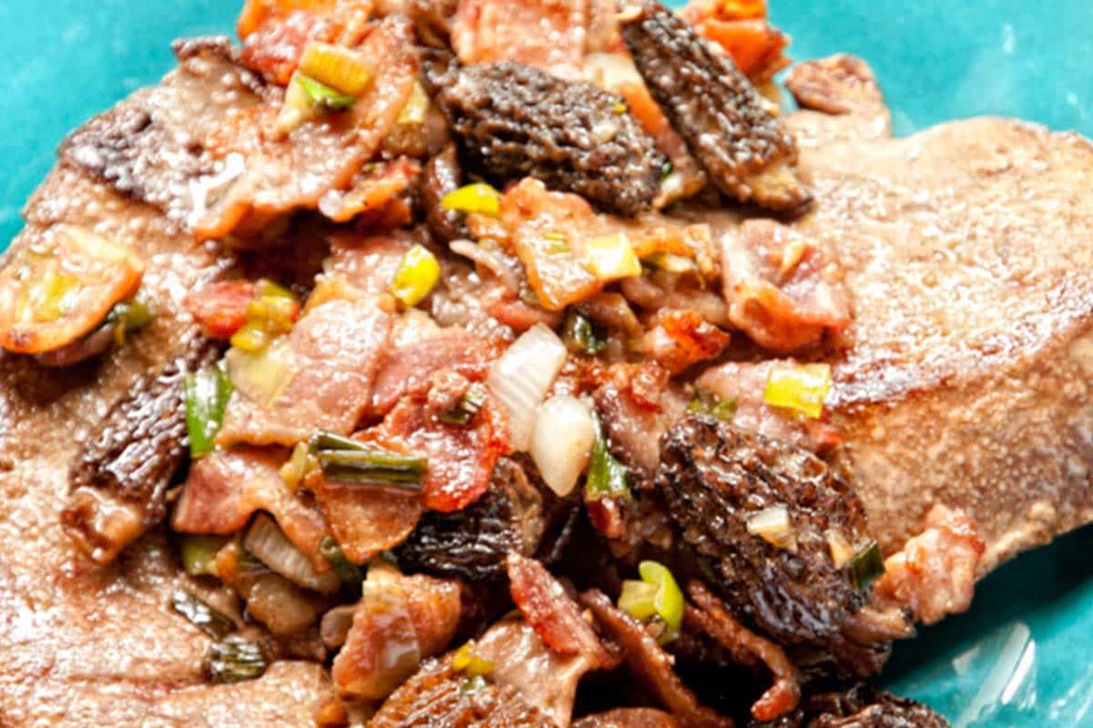 closeup of a serving of Grilled Liver with Bacon and Mushrooms on a blue plate