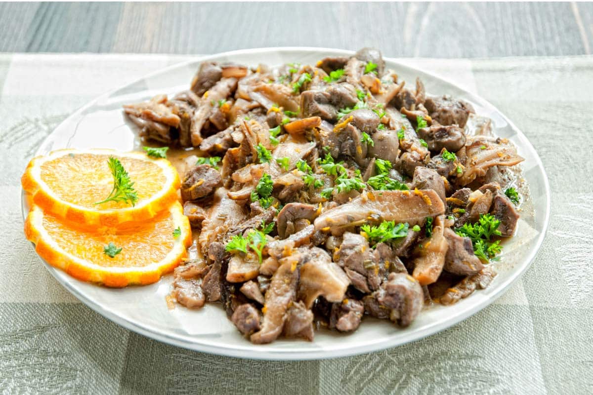 white plate full of Kidney and Orange Stew with orange slices