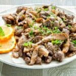 white plate filled with a serving of Kidney and Orange Stew with orange slices