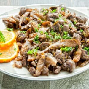 white plate filled with a serving of Kidney and Orange Stew with orange slices