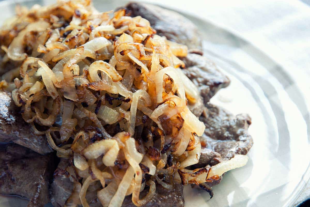 closeup of a serving of Liver and Onions on a white plate