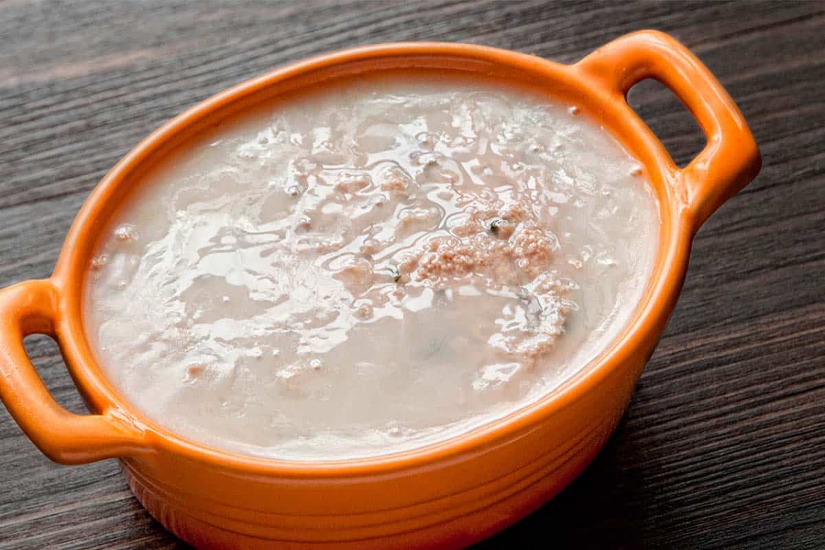 closeup of Pork Liver and Heart Pâté in an orange casserole dish on a wood table