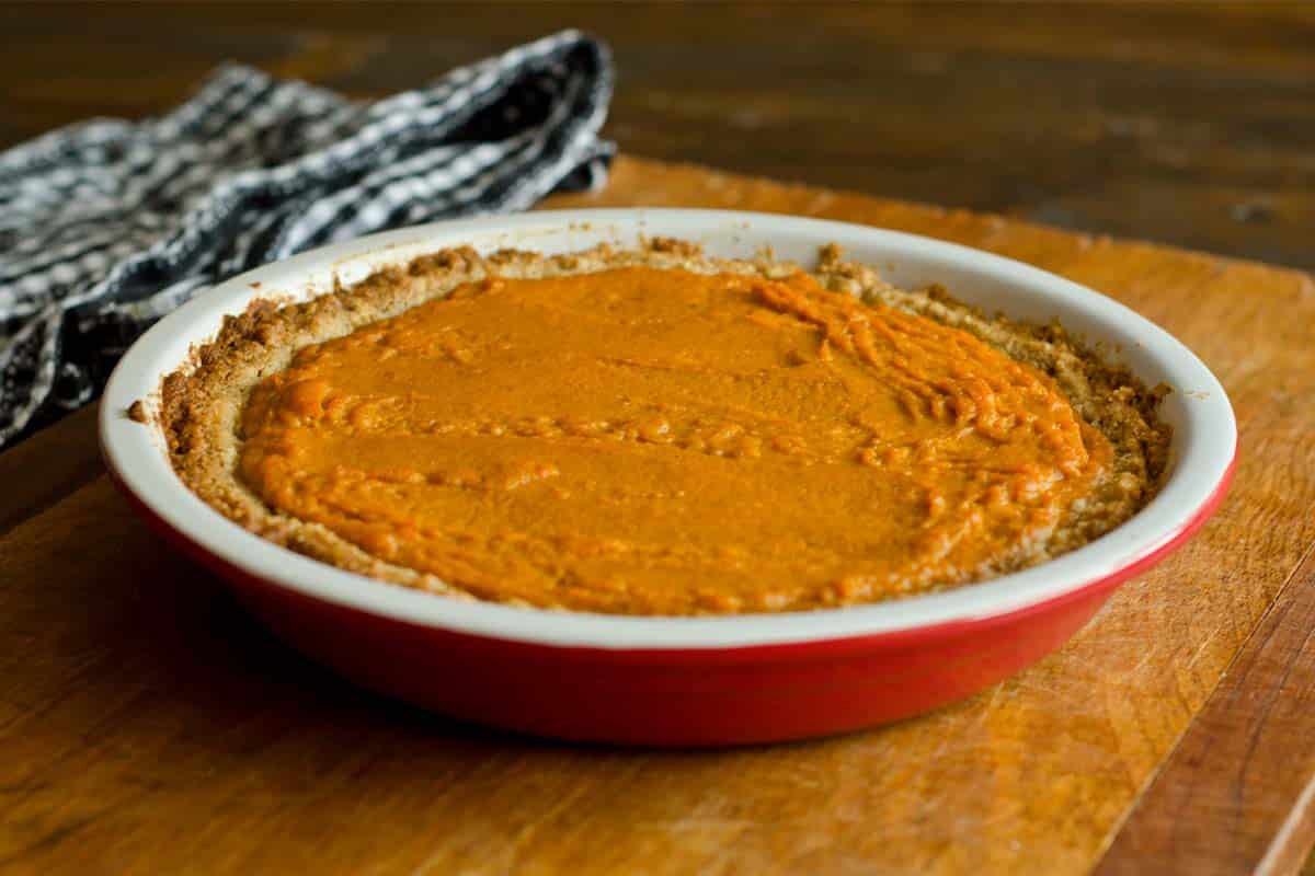 red pie plate filled with a paleo Pumpkin Pie on a wood table