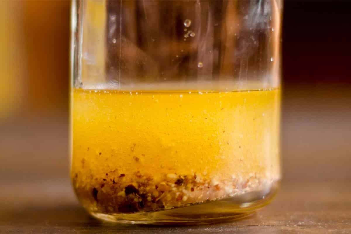 glass carafe full of Raspberry-walnut vinaigrette on a wood table