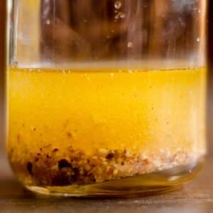 closeup of a glass carafe full of Raspberry-walnut vinaigrette on a wood table