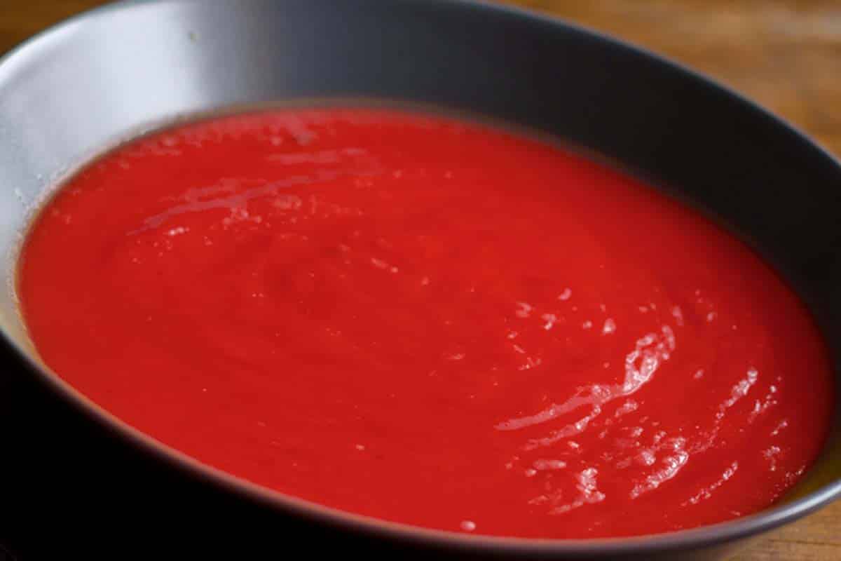 closeup of a black bowl of Red Beet Soup on a wood table