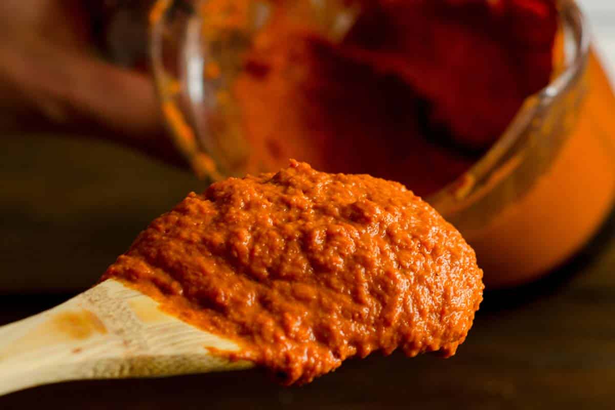 closeup of a wood spoon filled with Red curry paste 