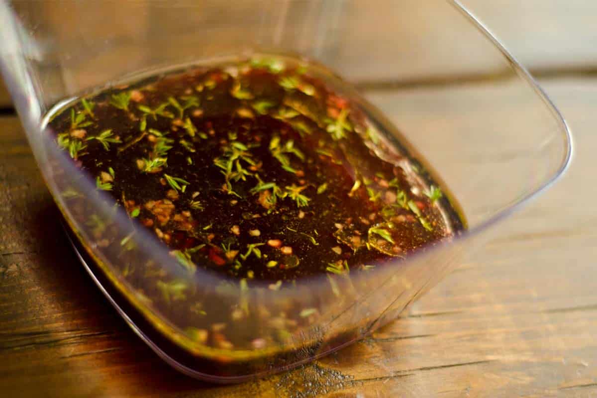 glass square bowl filled with Red Wine Garlic and Thyme Marinade on a wood table