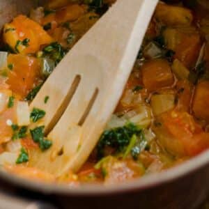 closeup of a pan of Sauce vierge warm dressing with a wooden spoon