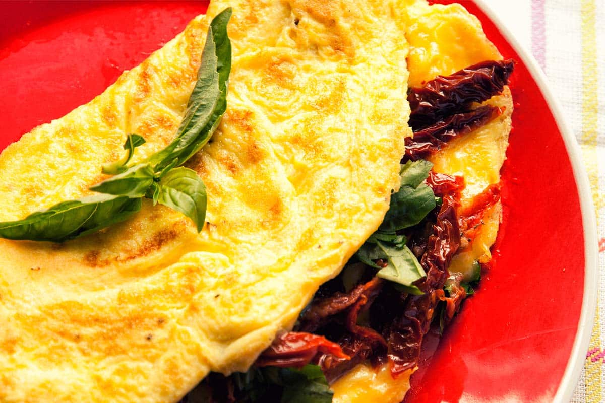 closeup of a red plate holding a Sun-dried tomato omelet