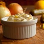 closeup of a ramekin of Tartar Sauce with onions in the background