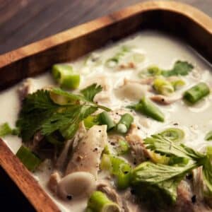 closeup of Thai chicken soup in a square wooden bowl