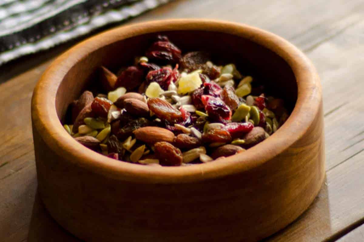 wood bowl filled with homemade trail mix on a wood table