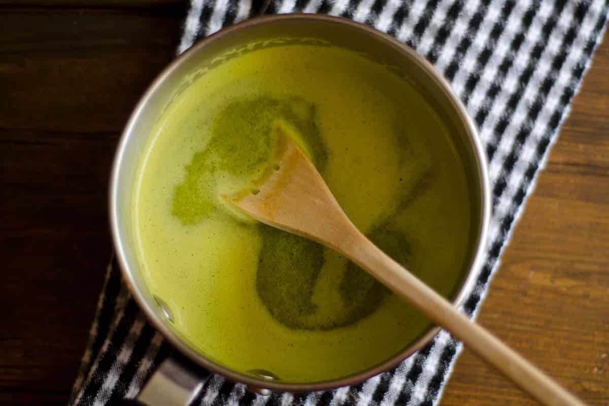 overhead view of Watercress sauce in a saucepan with a wood spoon