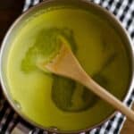 overhead view of a sauce pan full of Watercress sauce with a wood spoon